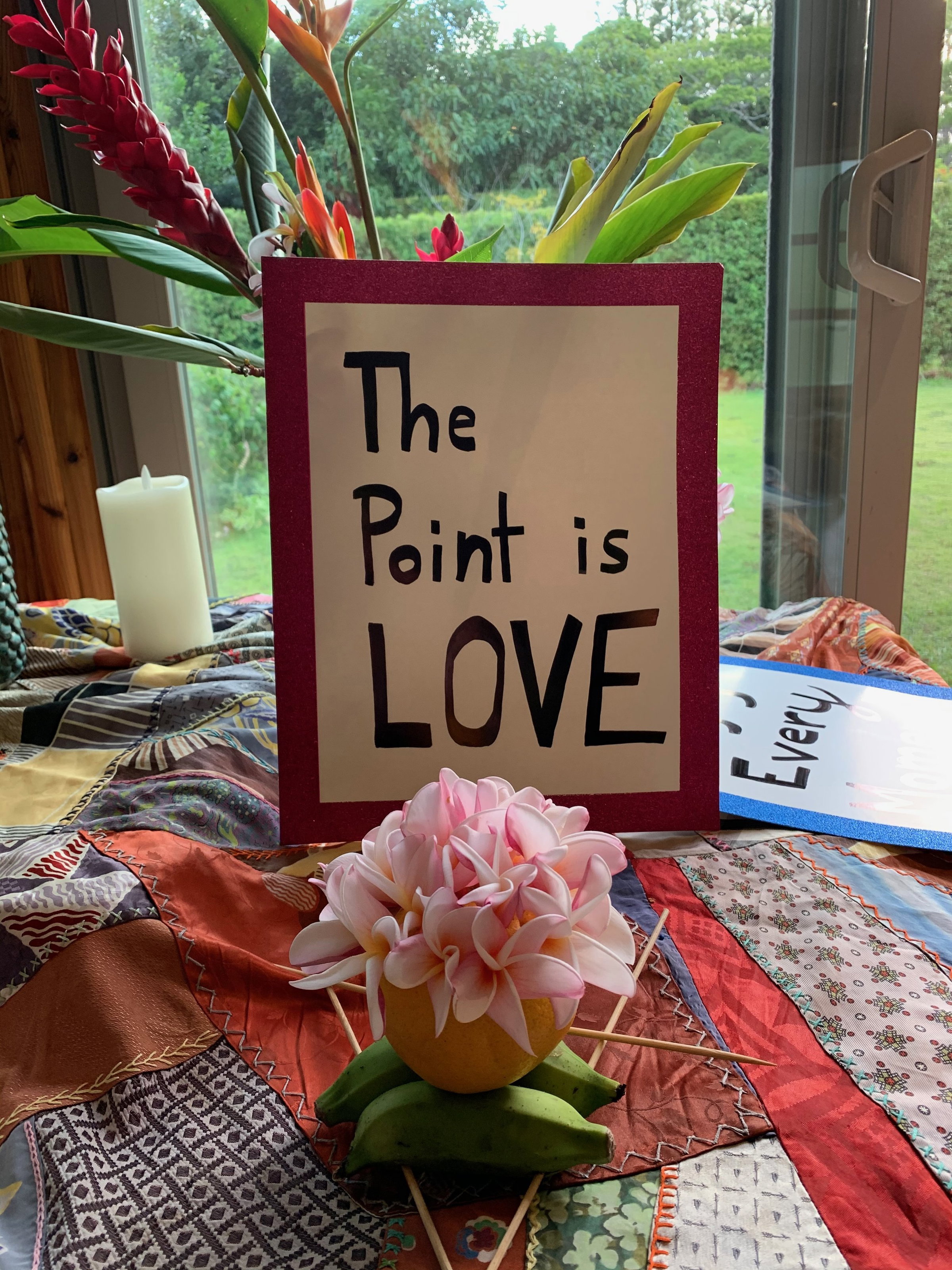 Framed sign reading "The Paint is Love" surrounded by flowers